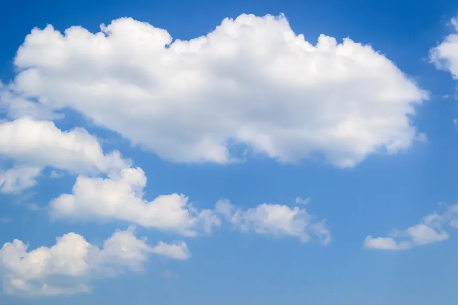 Several separate, puffy white clouds with rounded tops against a clear blue sky.