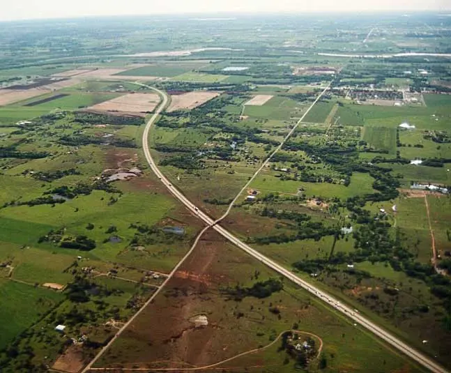 Aerial photograph of a dark scar cutting diagonally across Oklahoma farmland and crossing a divided highway.