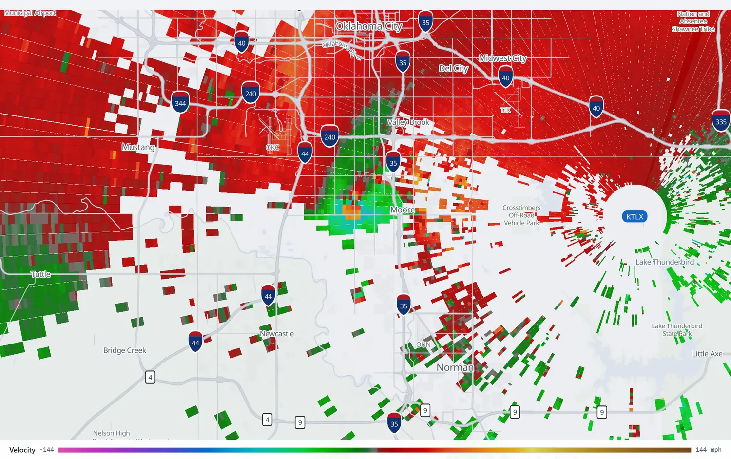 Radar velocity showing a tight pair of green inbound and red outbound gates immediately southwest of Moore.