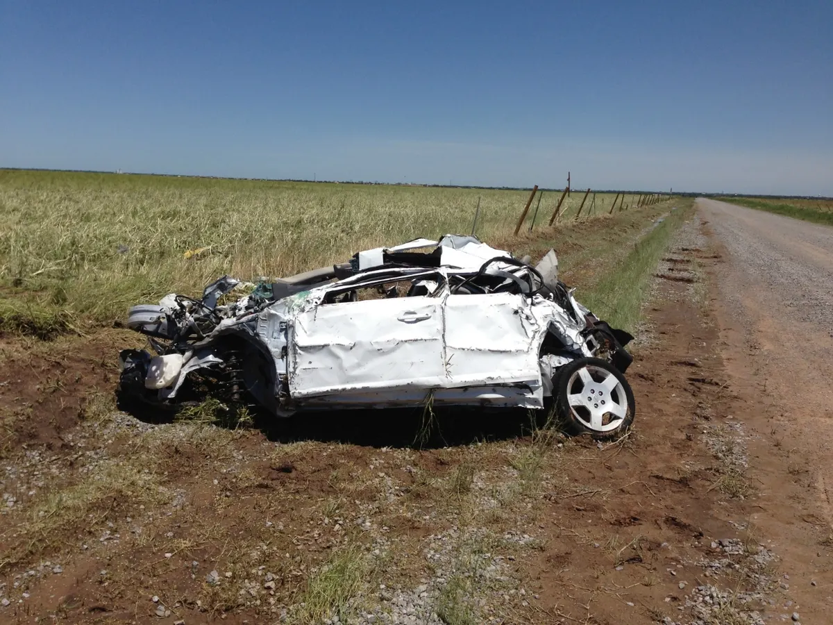 The crushed white Chevrolet Cobalt in a field, photographed during the National Weather Service damage survey.