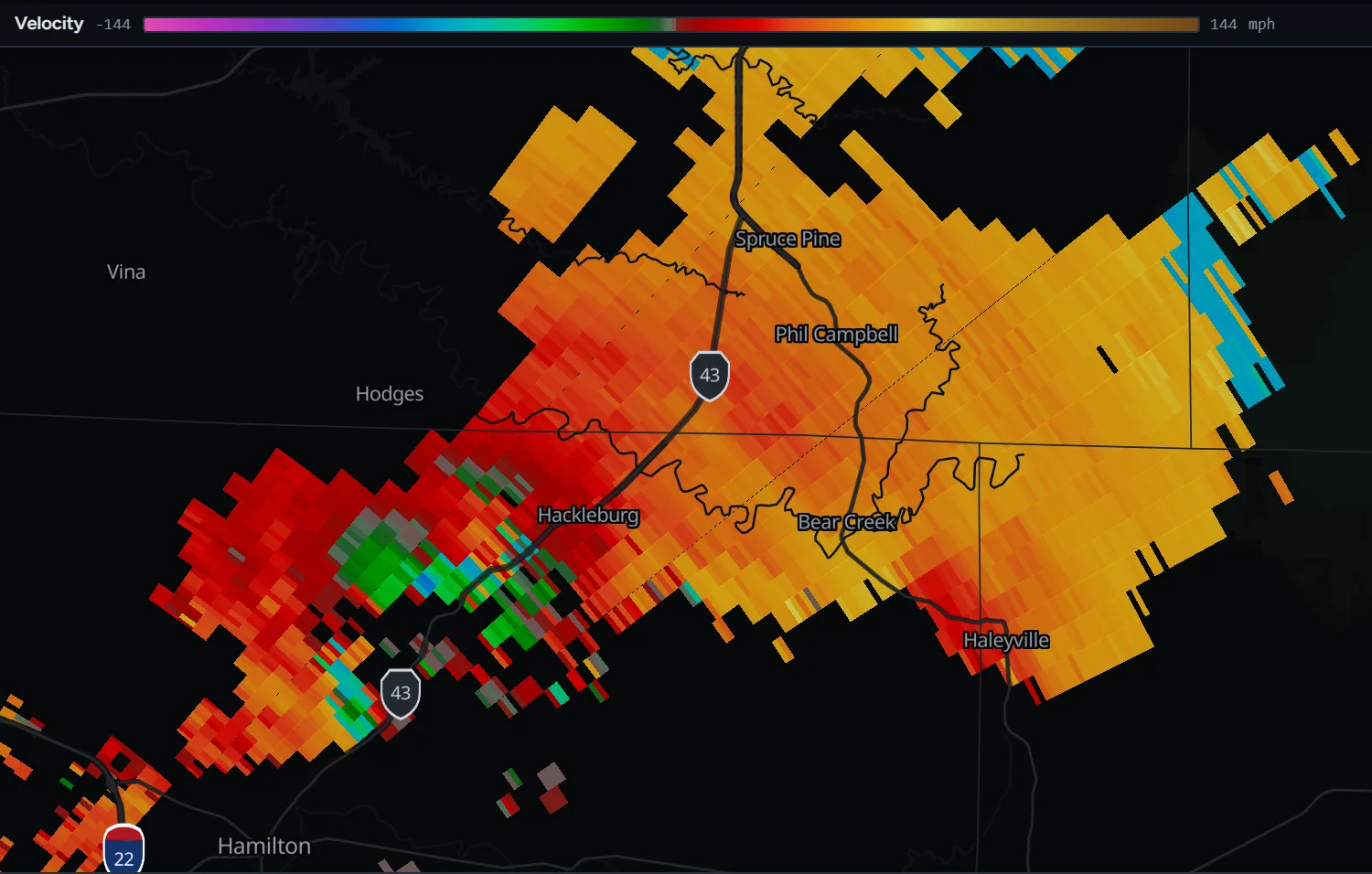 Radar velocity from KGWX showing a tight pair of green inbound and red outbound returns on the southwest edge of Hackleburg, Alabama, with broad outbound flow to the northeast.