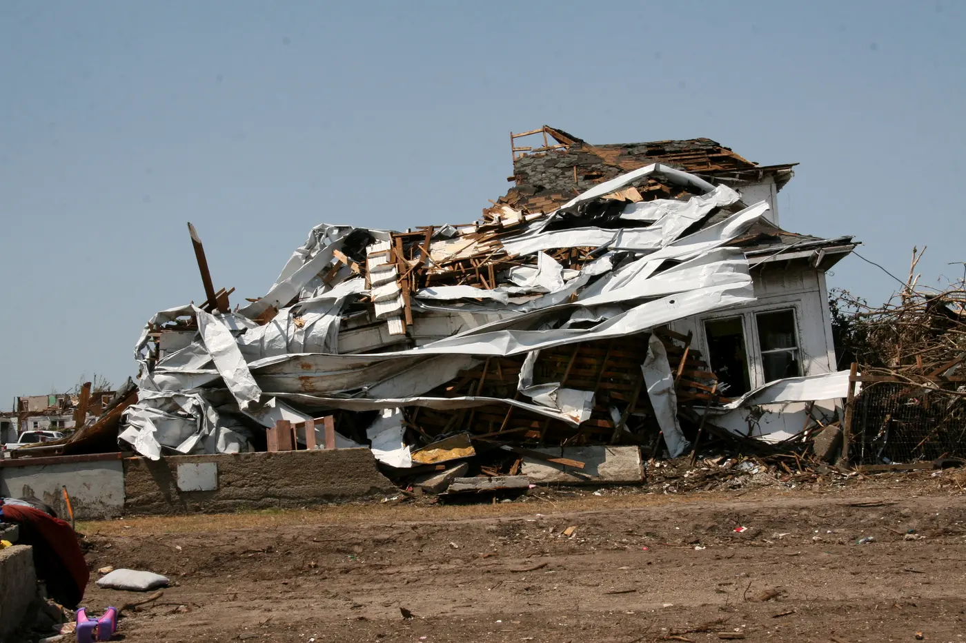 Metal roofing torn from a commercial building and wrapped around the frame of a house.
