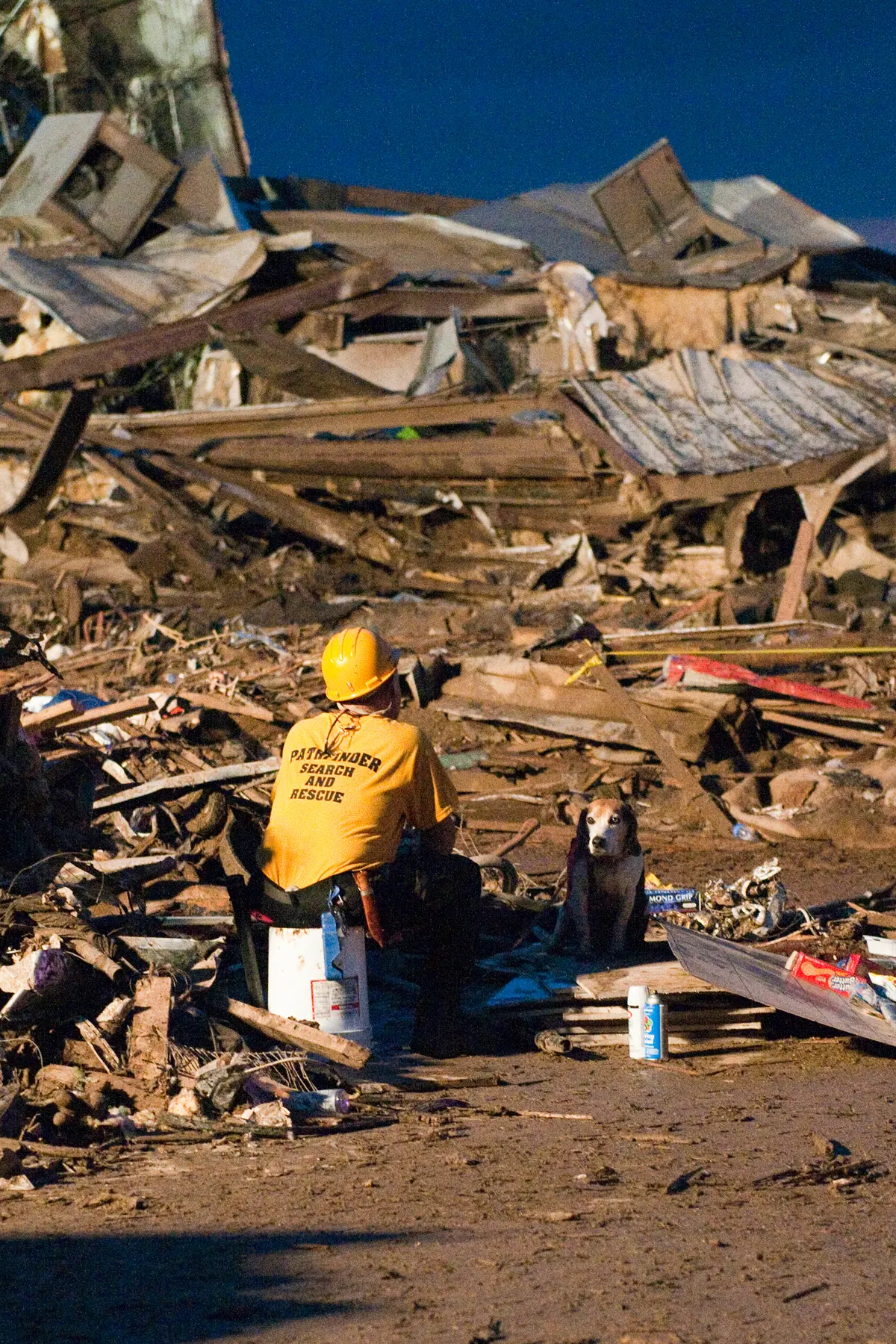 A rescue worker and a search dog resting beside the ruins of Plaza Towers Elementary School.