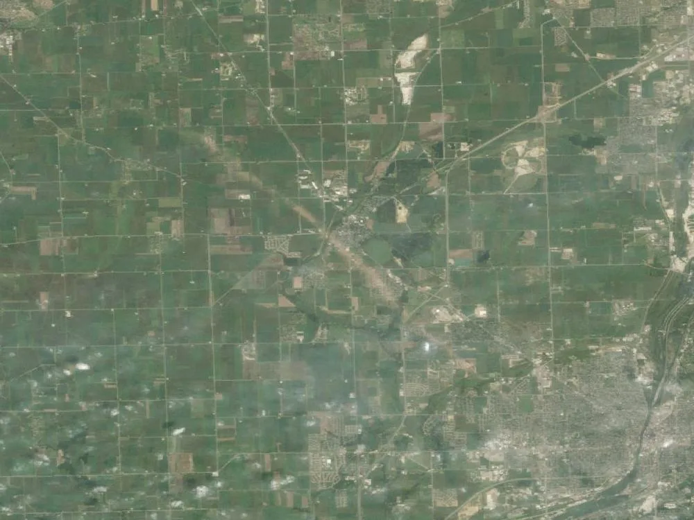 Landsat satellite image of farmland and suburbs southwest of Chicago with a faint pale diagonal streak running from upper left to lower right through Plainfield.