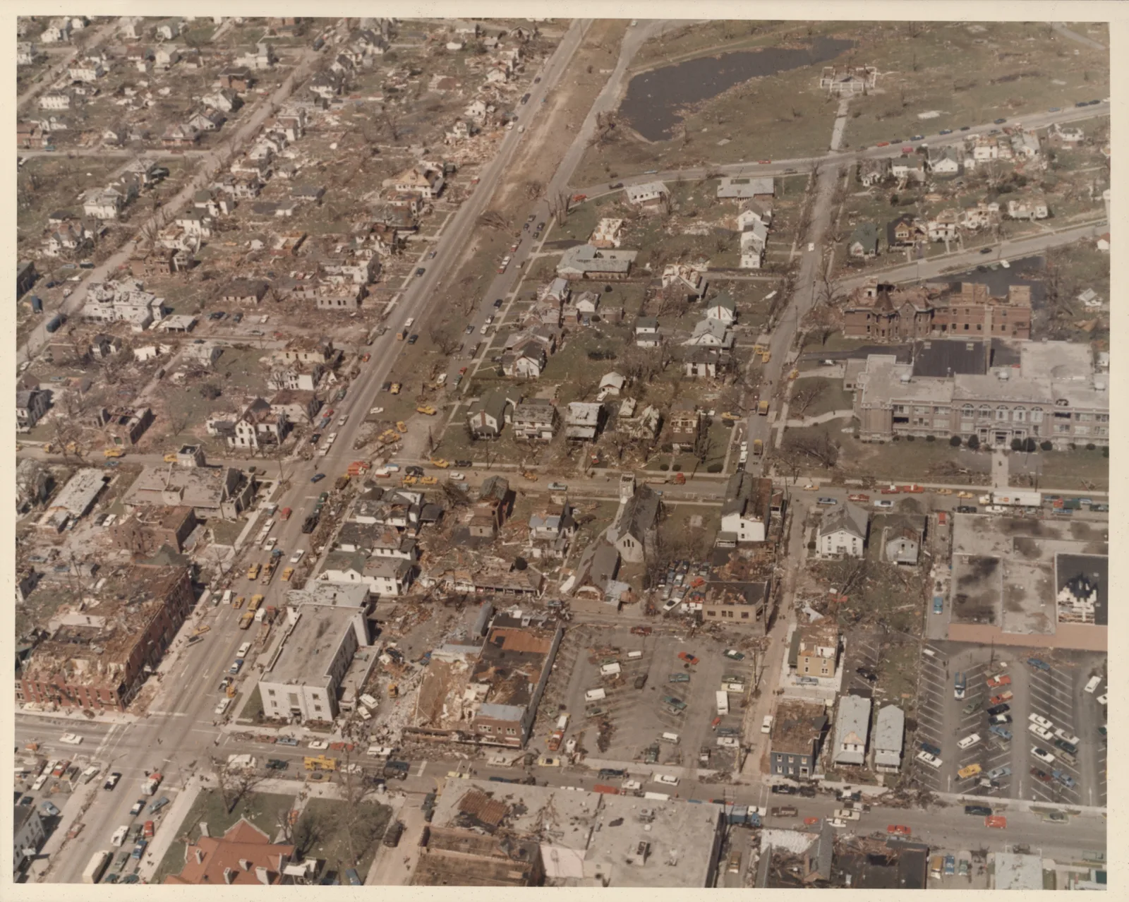 Aerial photograph of downtown Xenia after the tornado: a grid of streets with roofless brick buildings, houses stripped to frames, and lines of parked cars.